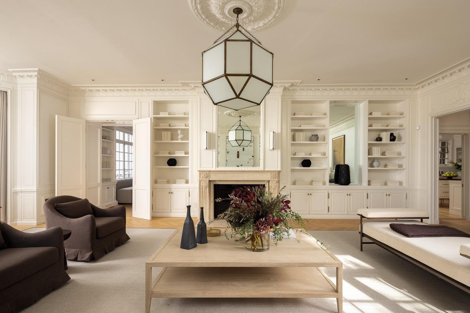 Spacious living room with white walls, built-in shelves, and modern lighting fixtures.
